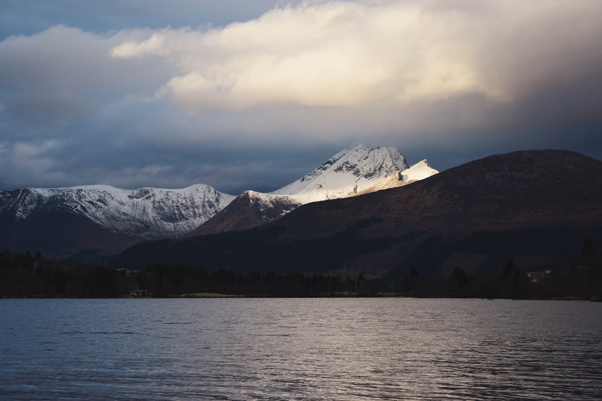 Snødekte fjell og fjord under skyer i Finnmark