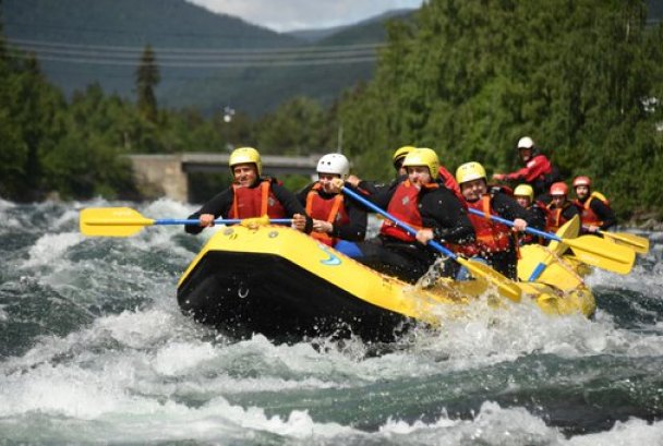 Gruppe i rafting-båt padler gjennom stryk i en elv